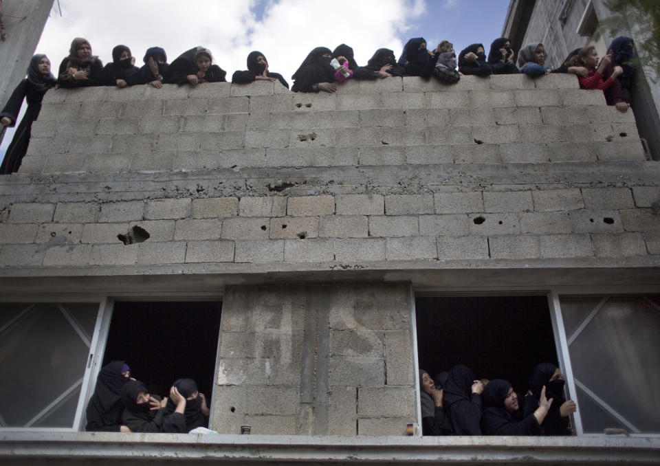 Relatives of Ahmed Abu Lebdeh, 22, who was killed by Israeli troops during Friday's protest at the Gaza Strip's border with Israel, look at mourners carry his body out of the family home during his funeral in town of Khan Younis, southern Gaza Strip, Saturday, Oct. 27, 2018. (AP Photo/Khalil Hamra)