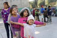 Migrant children line up as they play a game on a playground inside a shelter Wednesday, Dec. 21, 2022, in Tijuana, Mexico. Thousands of migrants gathered along the Mexican side of the southern border Wednesday, camping outside or packing into shelters as they waited for the U.S. Supreme Court to decide whether and when to lift pandemic-era restrictions that have prevented many from seeking asylum. (AP Photo/Marcio Jose Sanchez)