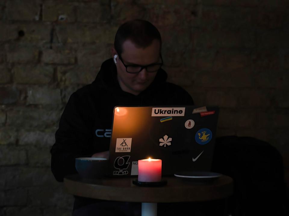 A man works on is computer with a candle.