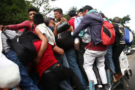 Honduran migrants, part of a caravan trying to reach the U.S., go up for a truck during a new leg of her travel in Zacapa, Guatemala October 17, 2018. REUTERS/Edgard Garrido