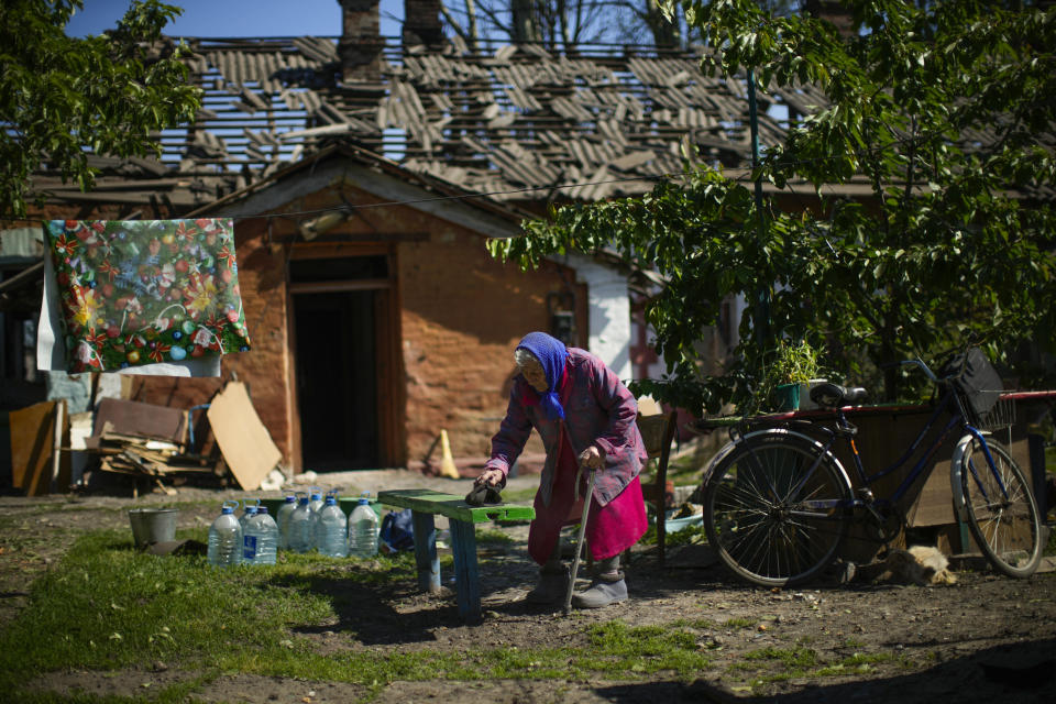 Local resident Valeria removes dust from a bench outside her heavily damaged house, background, after a Russian strike in Pokrovsk, eastern Ukraine, Wednesday, May 25, 2022. Two rockets struck the eastern Ukrainian town of Pokrovsk, in the Donetsk region early Wednesday morning, causing at least four injuries. (AP Photo/Francisco Seco)