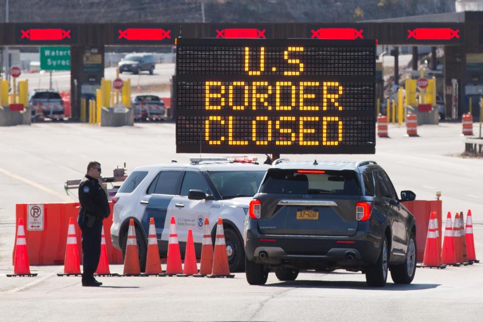 US Customs officers speaks with people in a car beside a sign saying that the US border is closed at the US/Canada border in Lansdowne, Ontario, on March 22, 2020. - The United States agreed with Mexico and Canada to restrict non-essential travel because of the coronavirus, COVID-19, outbreak and is planning to repatriate undocumented immigrants arriving from those countries. (Photo by Lars Hagberg / AFP) (Photo by LARS HAGBERG/AFP via Getty Images)