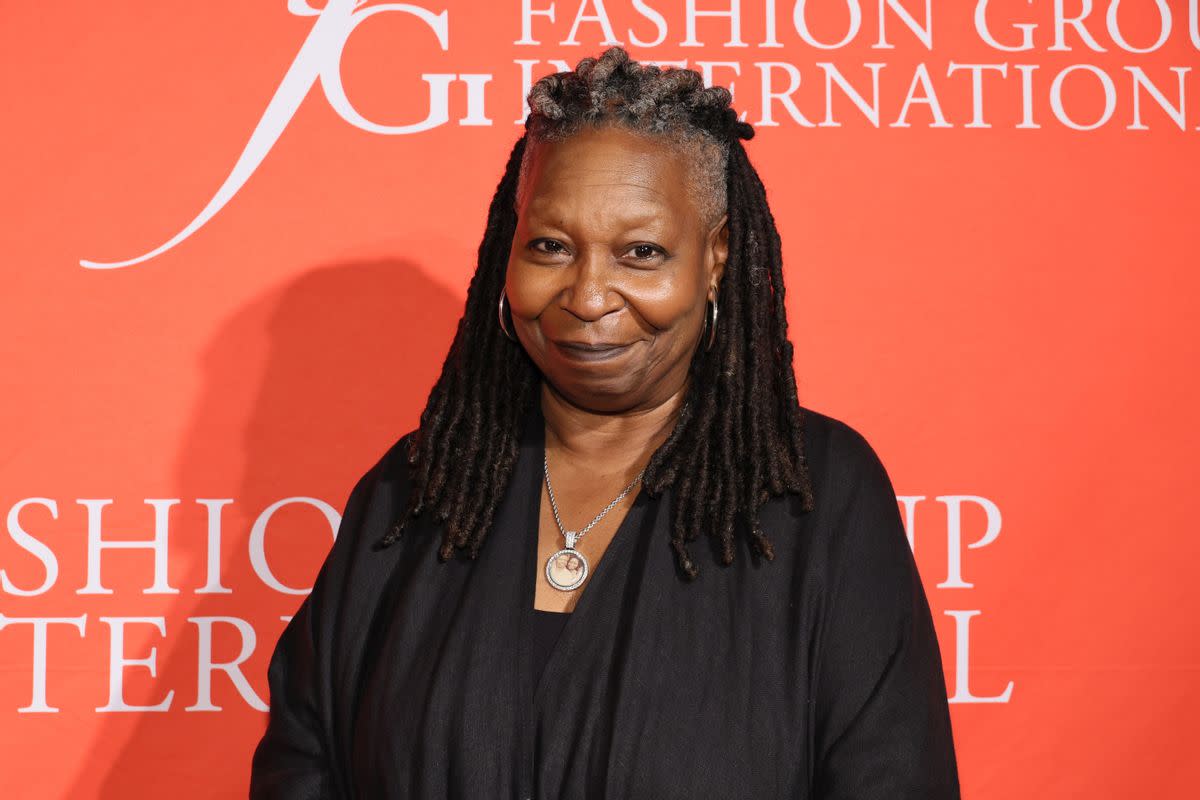 A Black woman wearing a black outfit smiles looking at the camera. 