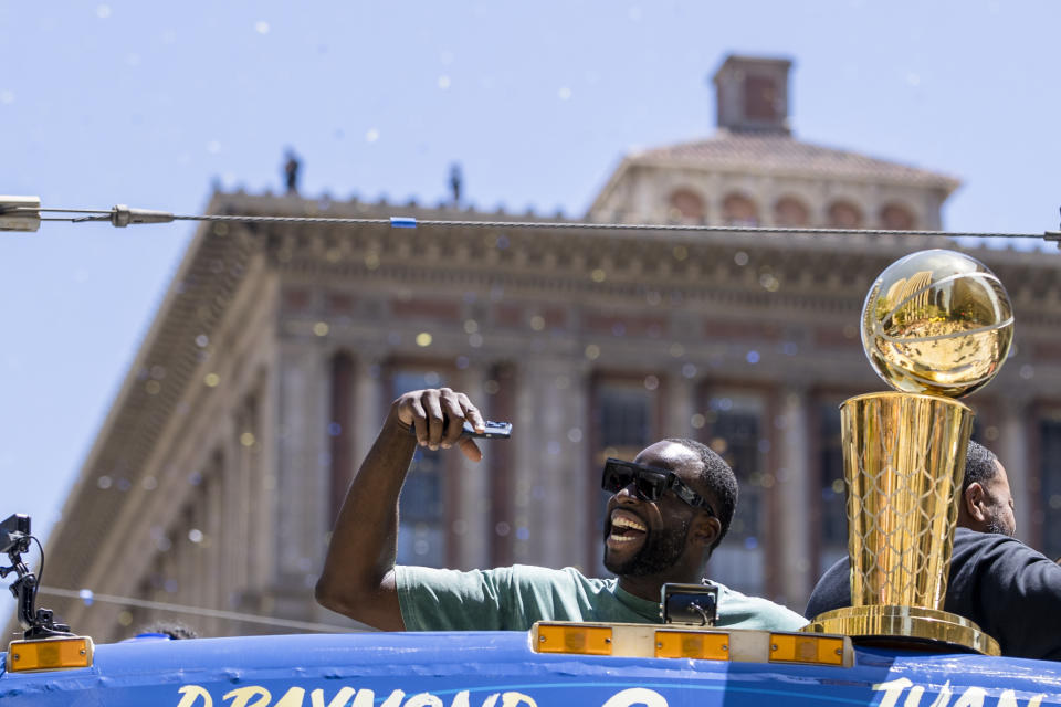 Golden State Warriors' Draymond Green waves to fans next to the Larry O'Brien trophy during the NBA Championship parade in San Francisco, Monday, June 20, 2022, in San Francisco. (AP Photo/John Hefti)