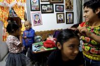 Hermes Soto gives a piece of cookie to her sister Linda Teoani Soto, as their mother, Esperanza Paz, combs the hair of the older sister, Africa Soto, at their house in Mexico City