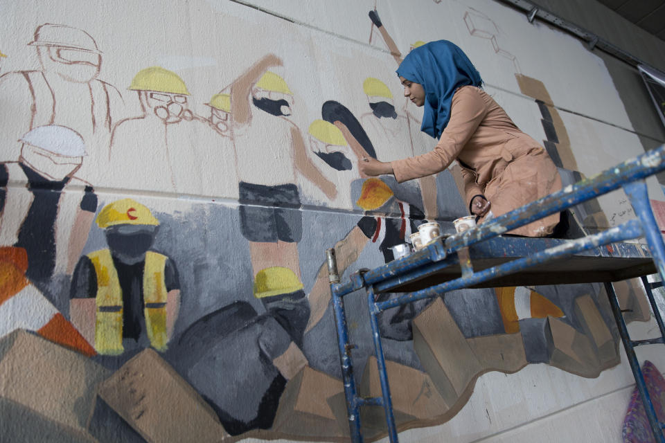 Iraqi street artist Sabah Ala', 18 works on a mural, in Baghdad, Iraq, Sunday, Dec. 8, 2019. (AP Photo/Nasser Nasser)