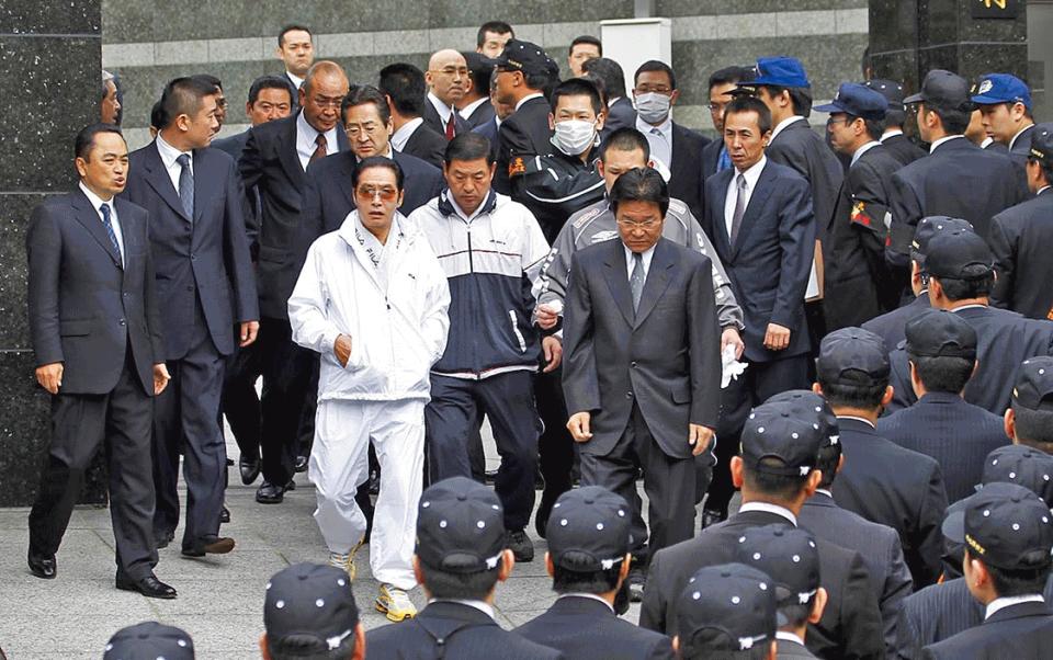 'Nomura was referred to as ‘the Emperor’ by his gang – and treated like one': Nomura (in white) during a house search in 2010 - Getty Images 