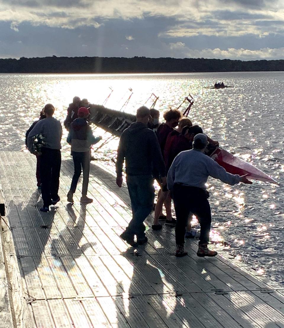A rowing crew team lowers its shell to the water of the South Watuppa Pond in Fall River as part of the Massachusetts Public School Rowing Association’s Fall Championship Regatta on Oct. 31, 2021.