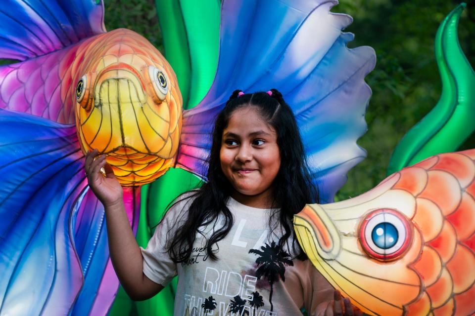 Melanie Cortez, 9, of Hudson, poses with illuminated Betta Fish during the Grand Rapids Lantern Festival at the John Ball Zoo on Wednesday, May 8, 2024.