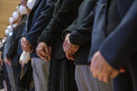 Residents stand as they watch a live broadcast of the memorial service for late former Chinese President Jiang Zemin on a screen at a community center in Hong Kong, Tuesday, Dec. 6, 2022. A formal memorial service was held Tuesday at the Great Hall of the People, the seat of the ceremonial legislature in the center of Beijing. (AP Photo/Vernon Yuen)