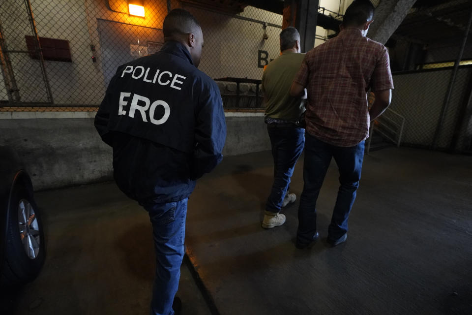 U.S. Immigration and Customs Enforcement agents transfer an immigrant into the ICE Metropolitan Detention Center in Los Angeles, after an early morning raid, Monday, June 6, 2022. This weekend, the Biden administration said it would suspend an order prioritizing the arrest and deportation of immigrants considered a threat to public safety and national security in order to comply with a ruling earlier in June 2022 from a Texas judge. Many otherwise law-abiding immigrants living here illegally will now be afraid to leave their homes out of concern they'll be detained. (AP Photo/Damian Dovarganes)