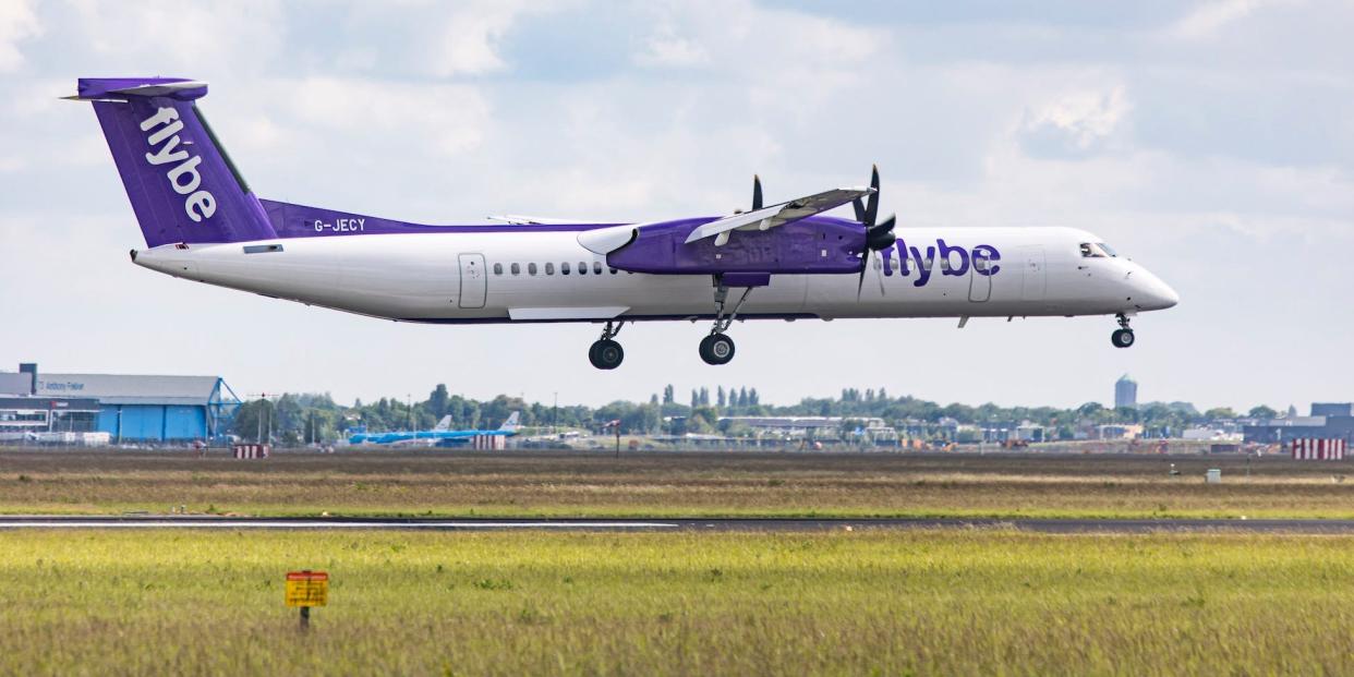 A Flybe plane landing with a field in the background