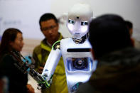 FILE PHOTO: People look at a RoboThespian humanoid robot at the Tami Intelligence Technology stall at the WRC 2016 World Robot Conference in Beijing, China, October 21, 2016. REUTERS/Thomas/File Photo