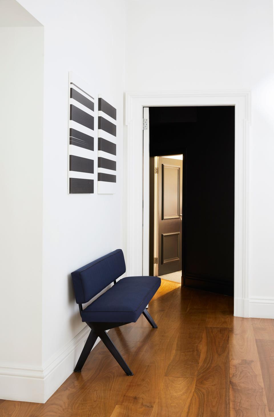 In the entryway, which leads to a black-walled bedroom hall, de la Cruz placed a dark-enameled Jean Prouvé bench and two black-and-white Wade Guyton paintings.