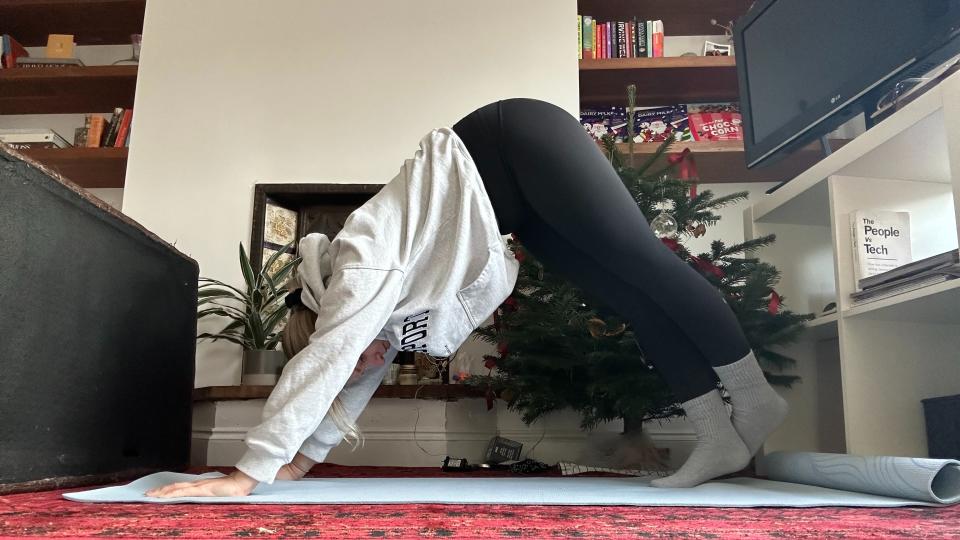 Woman doing downward dog variation in living room.