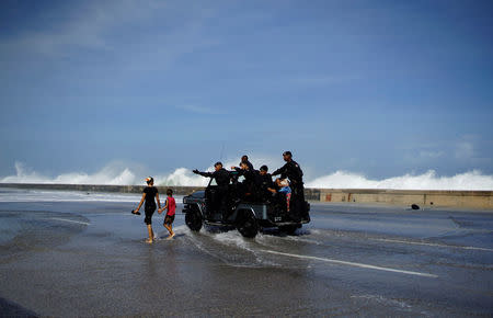 Security officers order two children to leave the area as waves crash at the seafront Malecon after Hurricane Irma caused flooding and a blackout, in Havana, Cuba September 11, 2017. REUTERS/Alexandre Meneghini