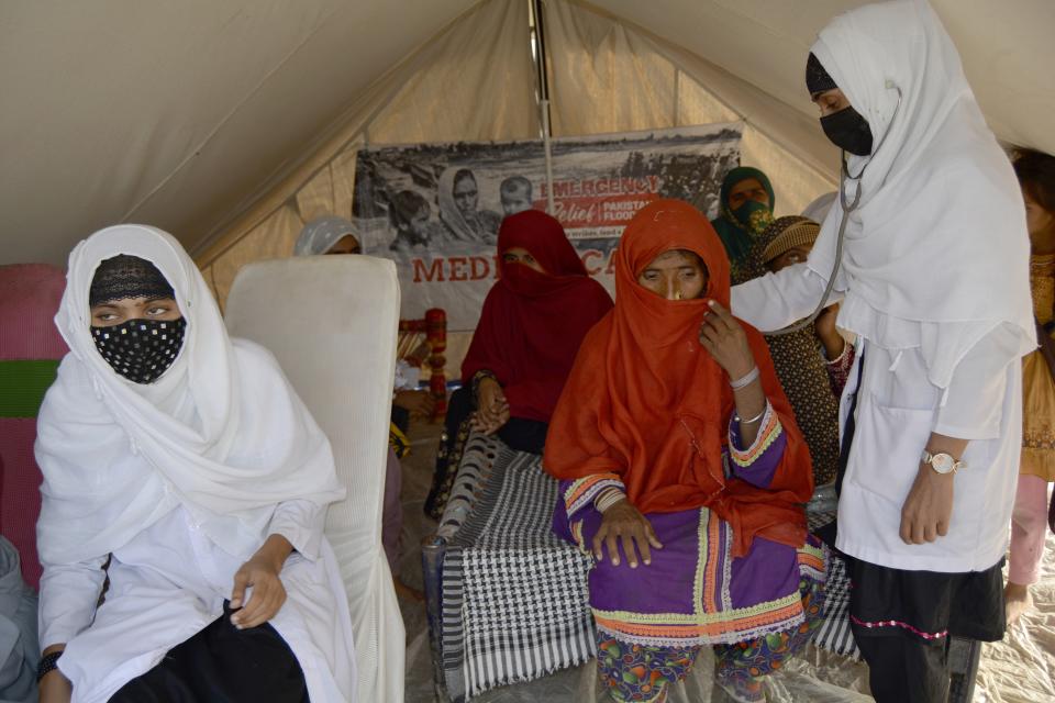 Pregnant women wait their turn for a checkup at a clinic setup in a tent at a relief camp for flood victims, in Fazilpur near Multan, Pakistan, Sept. 24, 2022. Pregnant women are struggling to get care after Pakistan’s unprecedented flooding, which inundated a third of the country at its height and drove millions from their homes. The UN says around 130,000 pregnant women in flood-hit areas require urgent healthcare and more than 2,000 are giving birth every day, most in unsafe conditions. (AP Photo/Shazia Bhatti)