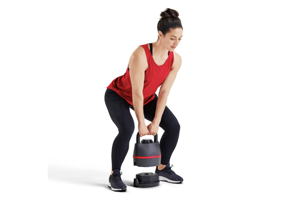 Girl squatting holding Bowflex kettlebell.