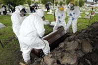 Cemetery and funeral workers lift a coffin containing the remains of a man who died of COVID-19, at the Zipaquira's Park Cemetery in Zipaquira, Colombia, Friday, June 18, 2021. Funeral workers in Colombia are struggling to dispose of bodies as the country experiences a surge in deaths from COVID-19. (AP Photo/Fernando Vergara)