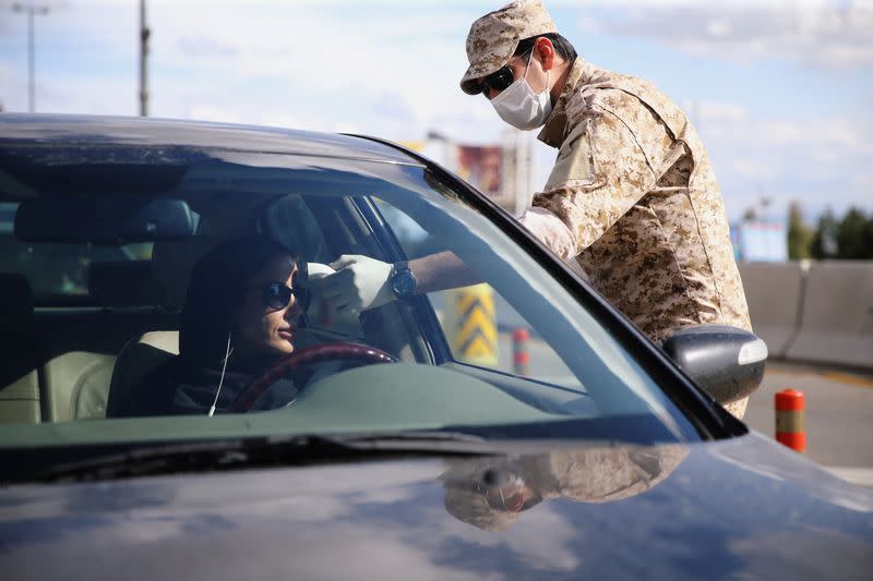 A member of the Islamic Revolution Guards Corps (IRGC) troops measures a temperature, following the outbreak of coronavirus disease (COVID-19) at the entrance of Qom