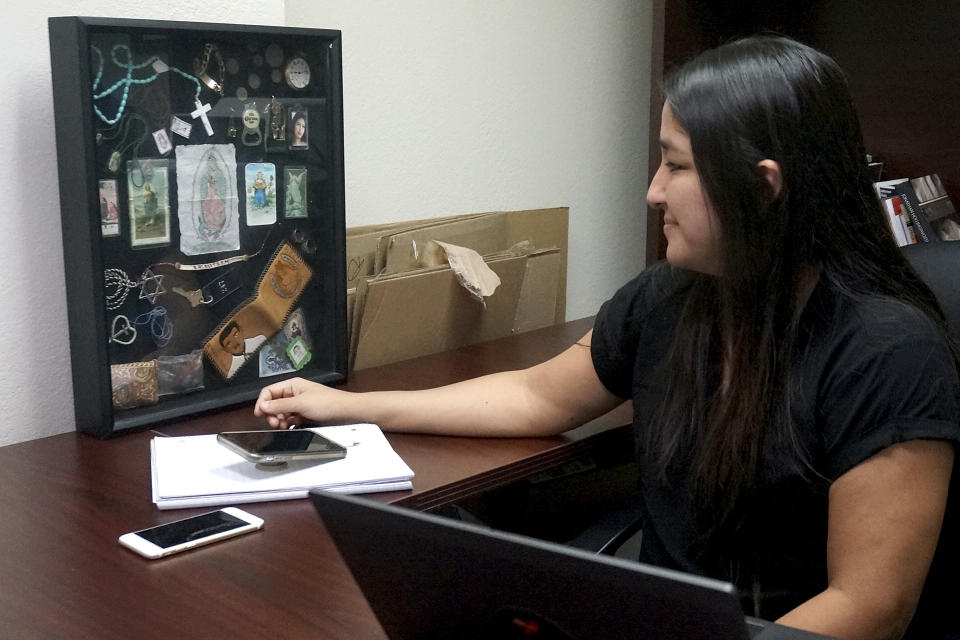 Mirza Monterroso, a forensic scientist and missing migrant program director for the Colibrí Center, a Tucson-based group that works with the Medical Examiner's office, looks at items found with missing migrants' remains, Wednesday, Sept. 7 2022, at the Mexican Consulate in Tucson, Ariz. The items her office collects are helpful with identifying remains of missing migrants. (AP Photo/Giovanna Dell'Orto)