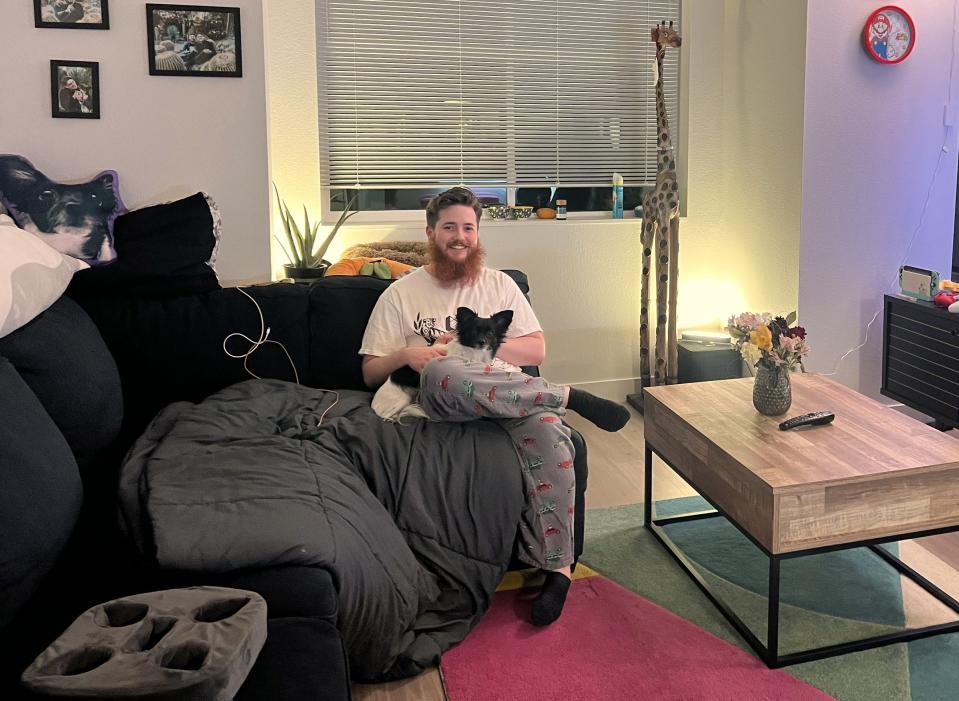 Oliver Bishop, 26, and his pet dog sit in the living room of Bishop's two-bedroom, two-bathroom apartment in a teacher housing complex in Pacifica, Calif. The Jefferson Union High School District said the housing helped recruit more educators.