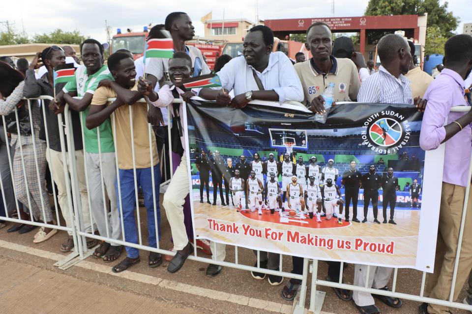 Supporters of the South Sudanese basketball team hold a banner as they wait to welcomed back, at Juba International airport, South Sudan, Tuesday, Sept. 5, 2023. Basketball has united the South Sudanese. The country which gained its independence just 12 years ago is still celebrating the men’s national team after its first-ever qualification for the Olympics. South Sudan will play at the Paris Olympics as the automatic qualifier from Africa thanks to a 101-78 win over Angola a week ago at the basketball World Cup in the Philippines. (AP Photo/Samir Bol)