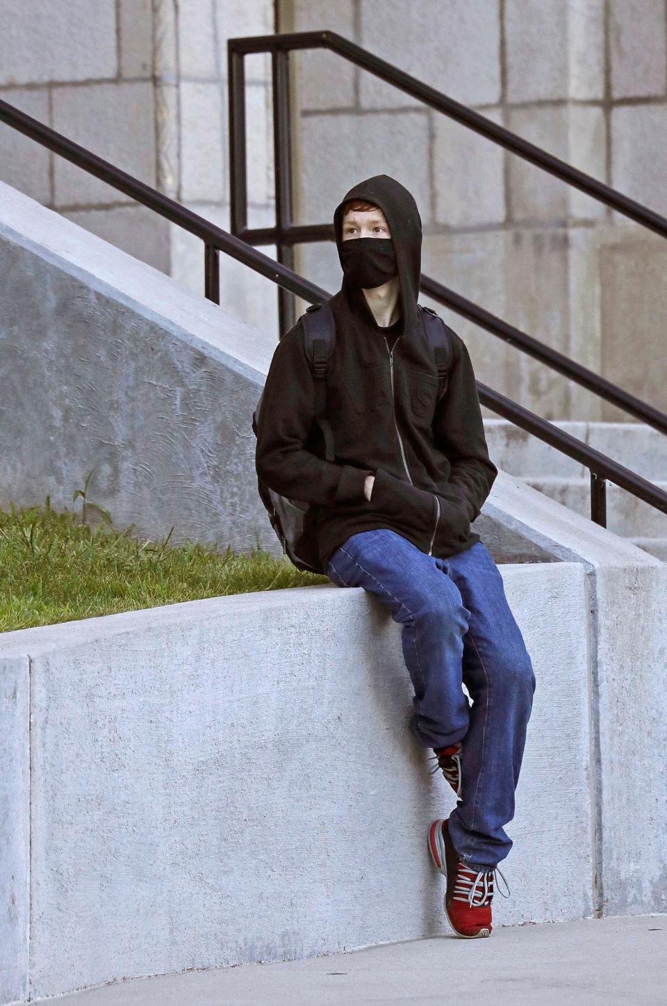 Nason Debauche, 18, waits near the entrance to Manitowoc Lincoln High School on the first day of classes, Monday, August 30, 2021, in Manitowoc, Wis. According to the district website, universal facial coverings will be required until conditions change in order to fight the COVID pandemic.