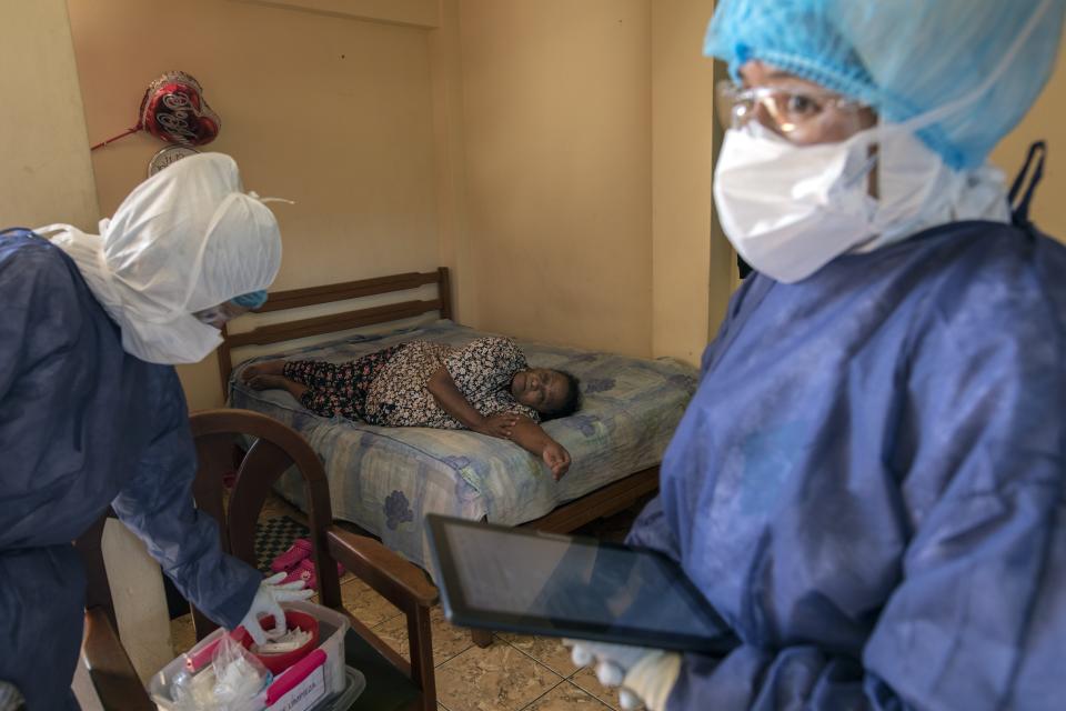FILE - In this April 15, 2020 file photo, Maria Teresa Carrillo rests on a bed as healthcare workers check the 87-year-old's results of COVID-19 antibody test, in Lima, Peru. In the early days of the pandemic, health officials of Peru faced a quandary. They knew molecular tests for COVID-19 were the best option -- but they didn't have the labs, the supplies, or the technicians to make them work. (AP Photo/Rodrigo Abd, File)