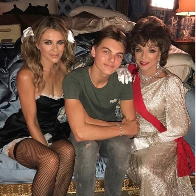 Liz Hurley posted this image to Instagram, showing her wearing a French maid's outfit as she sat alongside her son and Joan Collins. Photo: Instagram/Liz Hurley