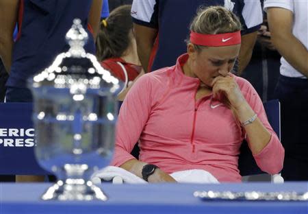 Victoria Azarenka of Belarus wipes her face as she sits by the winner's trophy (L) after being defeated by Serena Williams of the U.S. in their women's singles final match at the U.S. Open tennis championships in New York September 8, 2013. REUTERS/Eduardo Munoz