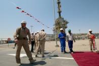 FILE PHOTO: A member of security foreign personnel stays guard next to Exxon's foreign staff and Iraqi staff of the West Qurna-1 oilfield, which is operated by ExxonMobil, during the opening ceremony near Basra