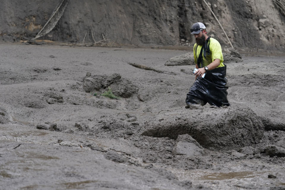 A worker with the Yucaipa Valley Water District threads through knee-deep mud while repairing a reservoir used as a drinking source in the aftermath of a mudslide, Tuesday, Sept. 13, 2022, in Oak Glen, Calif. (AP Photo/Marcio Jose Sanchez)