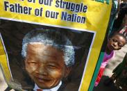 A girl looks at a poster depicting a photo of former South African President Nelson Mandela outside of Mandela's house in Johannesburg December 15, 2013. South Africa buries Nelson Mandela on Sunday, closing one momentous chapter in its tortured history and opening another in which the multi-racial democracy he founded will have to discover if it can thrive without its central pillar. REUTERS/Yves Herman (SOUTH AFRICA - Tags: OBITUARY POLITICS)