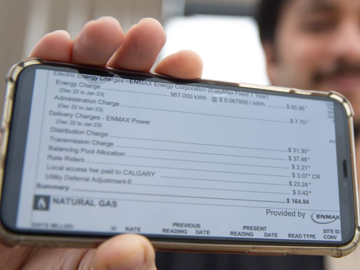 Shakeel Ahmed pictured with a copy of his utility bill in northwest Calgary. Ahmed says a large portion of his bill is made up of additional fees outside of his home's energy usage.  (Oseremen Irete/CBC - image credit)