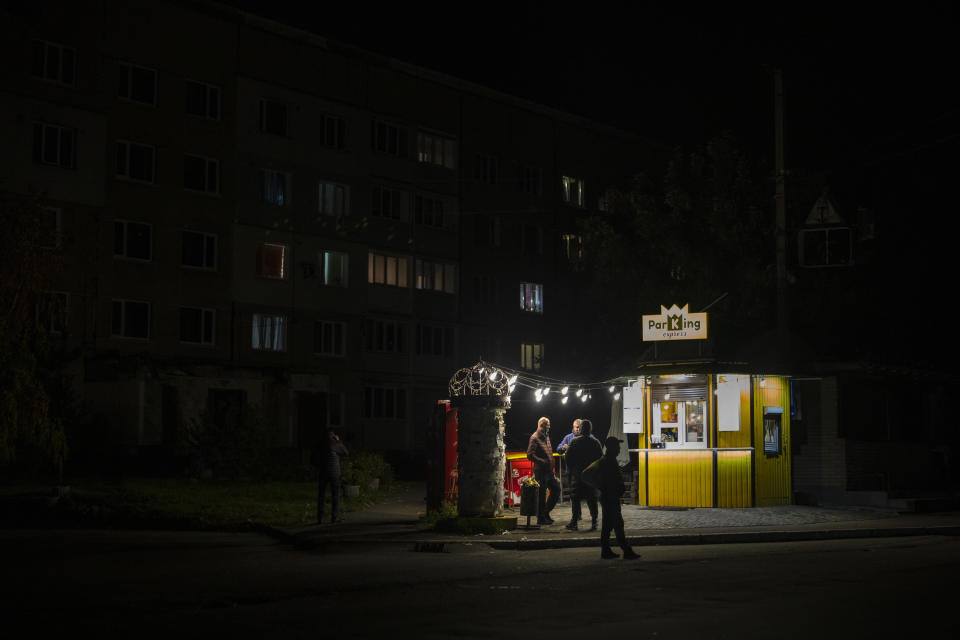 People stand outside a bar in Borodyanka, Kyiv region, Ukraine, Friday, Oct. 21, 2022. Russia has declared its intention to increase its targeting of Ukraine's power, water and other vital infrastructure in its latest phase of the nearly 8-month-old war. Ukrainian President Volodymyr Zelenskyy says that Moscow's forces have destroyed nearly a third of the country's power stations since Oct. 10. (AP Photo/Emilio Morenatti)