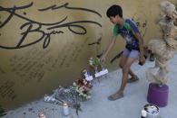 A boy places flowers on a wall with an image and signature of former NBA basketball player Kobe Bryant at the "House of Kobe" basketball court in Valenzuela, north of Manila, Philippines on Monday, Jan. 27, 2020. (AP Photo/Aaron Favila)