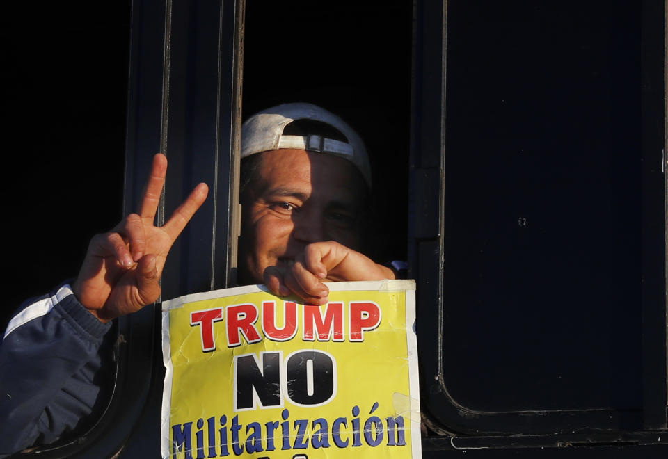 A migrant traveling with a caravan hoping to reach the U.S. border, holds a sign with a message that reads in Spanish: "Trump, No to militarization of the border," after boarding a bus in La Concha, Mexico, Wednesday, Nov. 14, 2018. Buses and trucks are carrying some migrants into the state of Sinaloa along the Gulf of California and further northward into the border state of Sonora. The bulk of the main caravan appeared to be about 1,100 miles from the border, but was moving hundreds of miles per day. (AP Photo/Marco Ugarte)