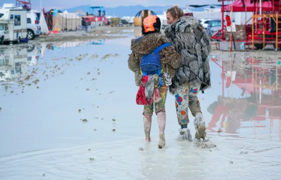 Festivalgoers walk through the mud at Burning Man (Trevor Hughes USA Today Network)