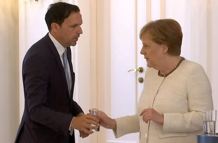 German Chancellor Angela Merkel receives water as she was seen shaking meeting President Frank-Walter Steinmeier in Berlin