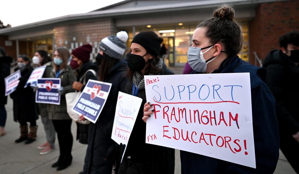 Michelle McGahan, right, a career development program coordinator at Framingham High School, holds a sign as students arrive for school during a teacher standout to call attention to an expired contract, Jan. 19, 2021. Framingham teachers have been working under a contract that expired in August.