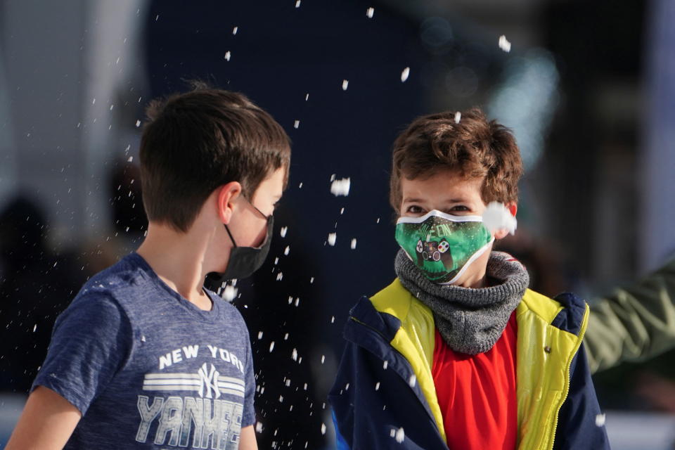 Children wearing protective masks toss snow at each other as they skate at Bryant Park in New York City, January 14, 2022. REUTERS/Carlo Allegri