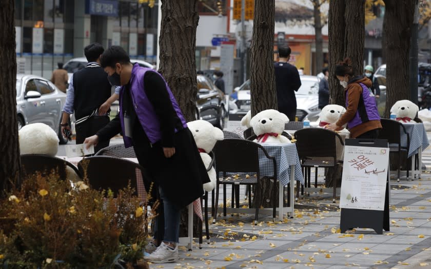 Tables and chairs are placed with hand sanitizers and stuffed toys while maintaining social distancing in downtown Seoul, South Korea, Wednesday, Nov. 18, 2020. This is one of the programs for a week, for the people who are tired from COVID-19, can enjoy while maintaining social distancing and for downtown revitalization. (AP Photo/Lee Jin-man)