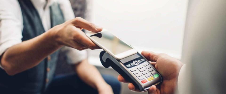 Man using his phone to pay, tapping on interac machine