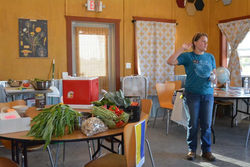 Saxon Brown with Columbia Center for Urban Agriculture showcases produce Monday grown from the CCUA gardens at Clary-Shy Park as part of a Welcome Week activity from Catholic Charities Refugee Services. 