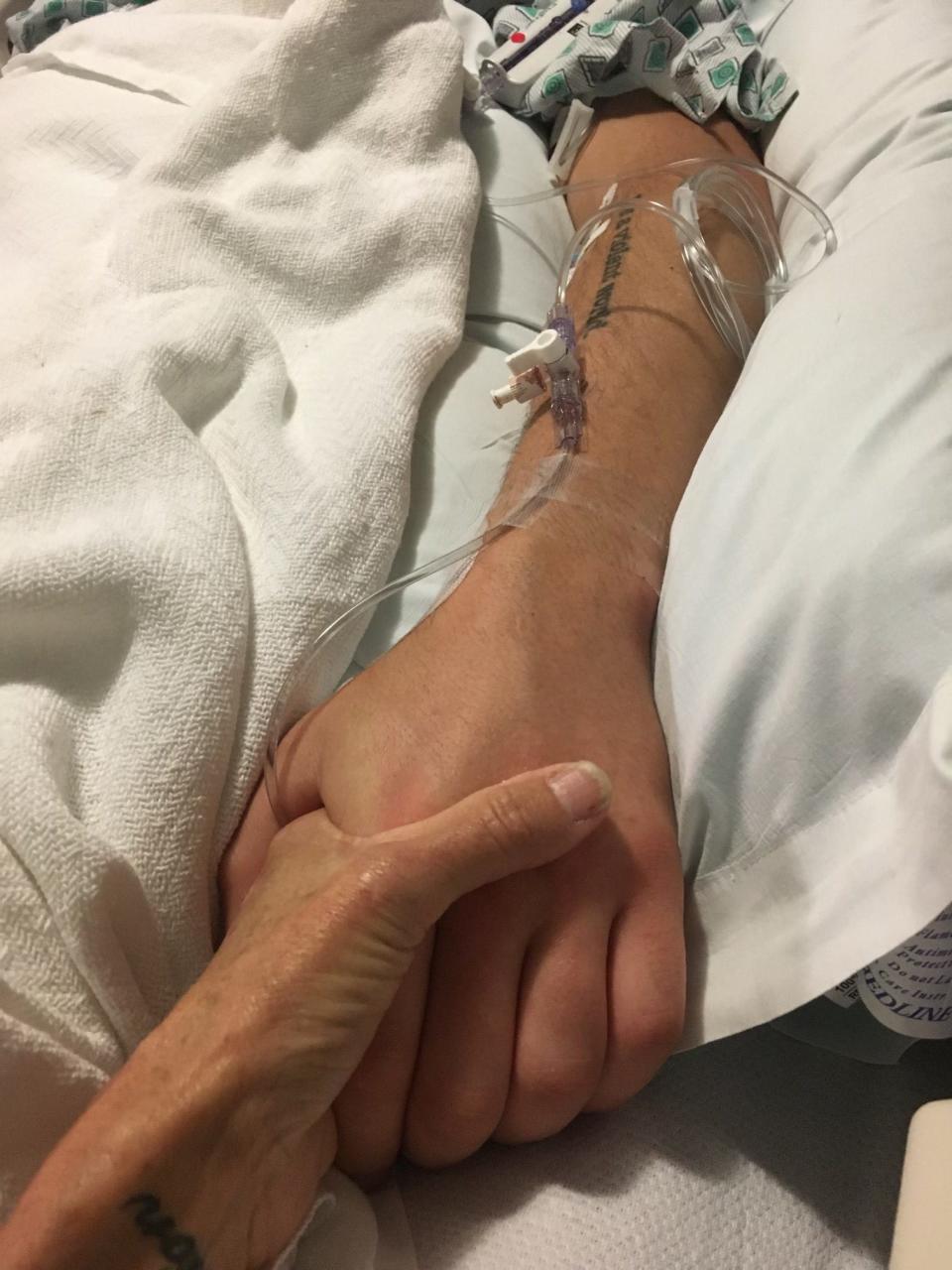 A mother holds her son's hand after he overdosed.