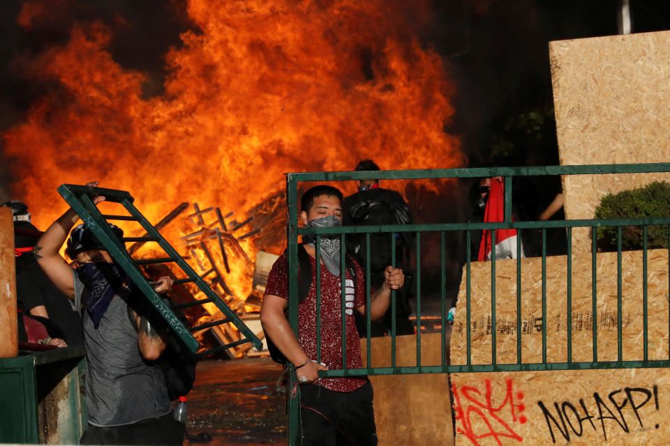 Demonstrators react as fire rages during an anti-government protest in Santiago, Chile on Oct. 28, 2019. (Photo: Henry Romero/Reuters)