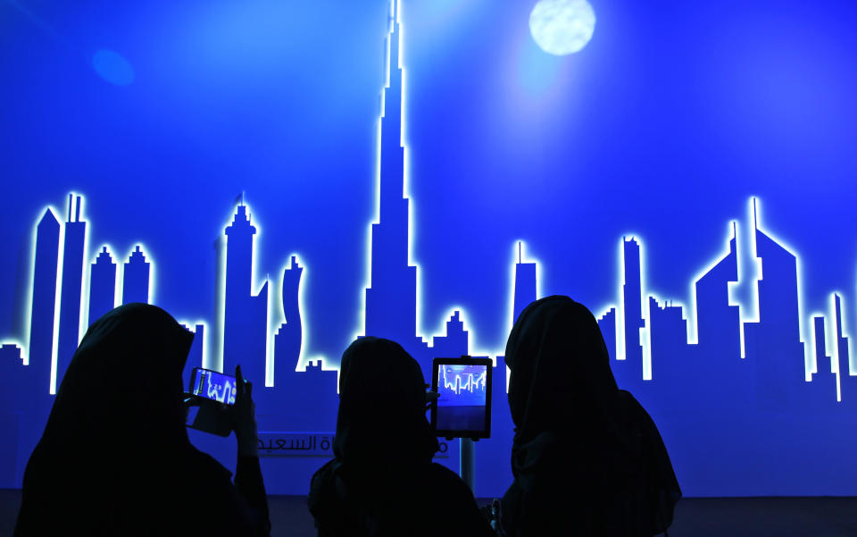 Emirati attendees take photos of an image of the city's skyline in Dubai, United Arab Emirates, Wednesday, March 5, 2014. After years of chasing the biggest and the best, the fast-growing Mideast city of Dubai is turning to technology to help the little things in life run more smoothly. (AP Photo/Kamran Jebreili)