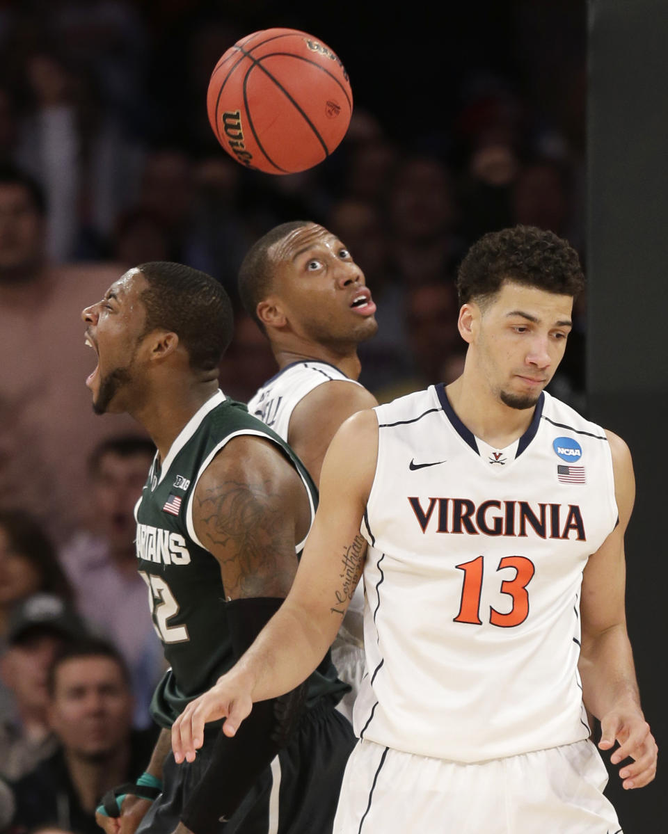 Michigan State's Branden Dawson, left, reacts after scoring, next to Virginia's Akil Mitchell, center, and Anthony Gill during the second half of a regional semifinal at the NCAA men's college basketball tournament, Friday, March 28, 2014, in New York. (AP Photo/Seth Wenig)