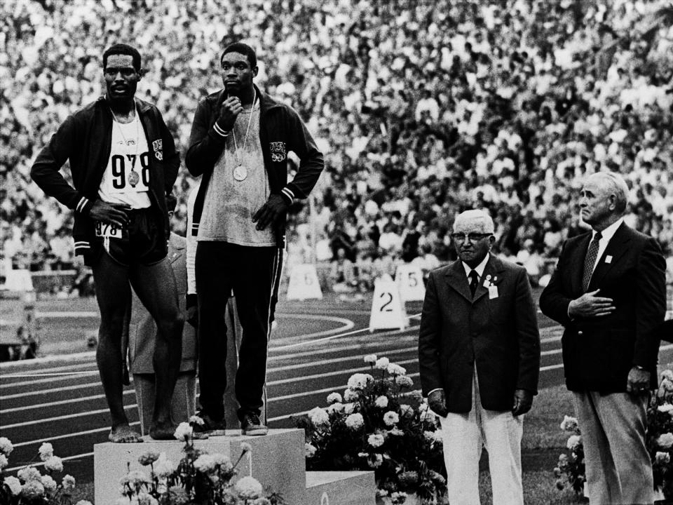 FILE - U.S. runners Wayne Collett (978) and Vince Matthews stand at ease on the top level of the victory stand Sept. 7, 1972, at Olympic Stadium in Munich. The International Olympic Committee banned the two from further competition although Matthews said later that no disrespect was intended. The IOC says it will allow American gold-medal sprinter Matthews back at the games more than 50 years after banning him for his low-key racial injustice protest at the Munich Olympics. (AP Photo, File)